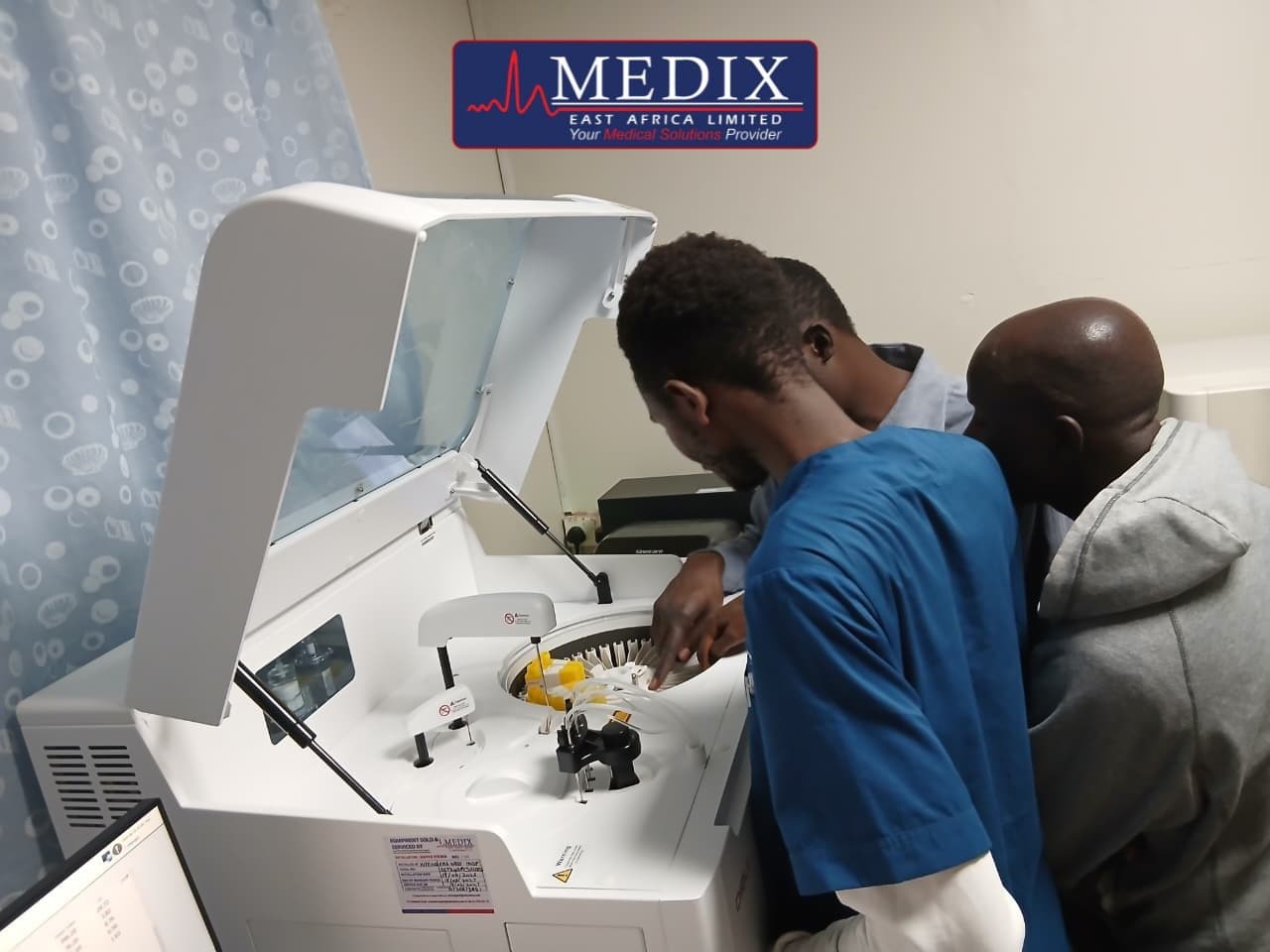 Laboratory staff loading samples into a chemistry analyser during commissioning